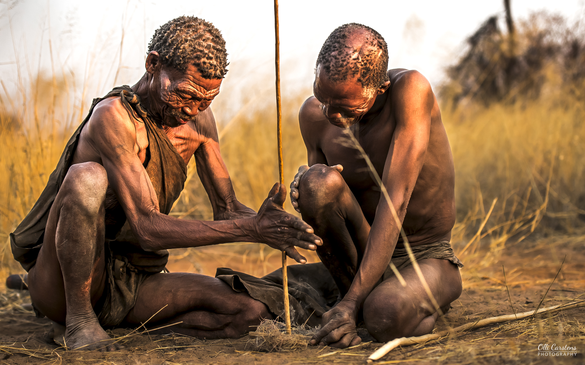 Die Ureinwohner Namibias erleben mit Buschmann Safaris. Zwei Männer, die während der Jagd im Freien mit einem Stock arbeiten.